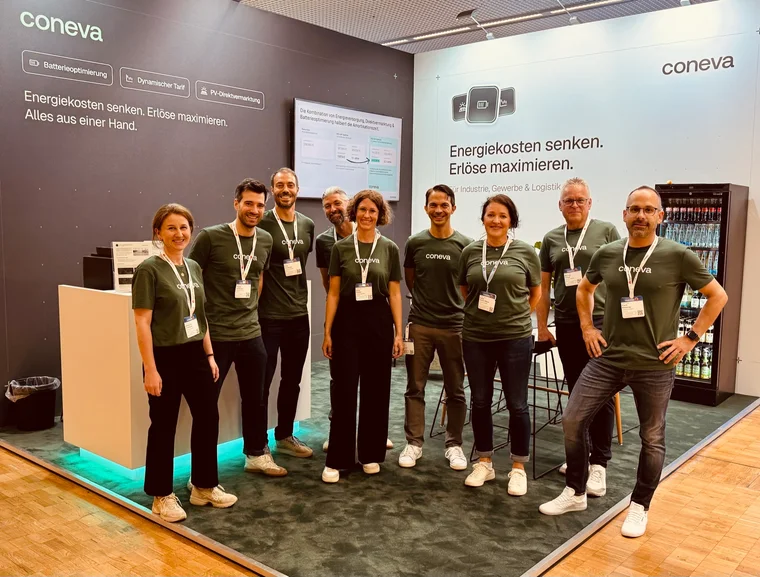 Das coneva-Team am Messestand vor der Standwand mit dem Schriftzug „Energiekosten senken. Erlöse maximieren.“